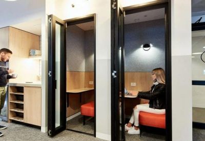 Individual soundproof phone booths with orange stools and integrated desks.