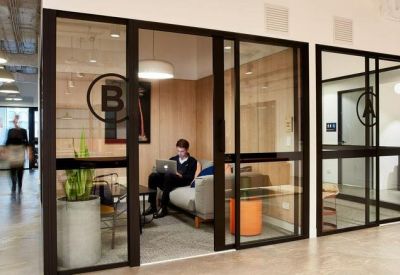 Glass-enclosed private meeting room with timber walls and a potted plant.