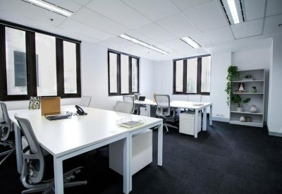 Open-plan office space with multiple desks and shelves.