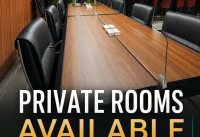 Long wooden conference table with black leather chairs and a glass divider.