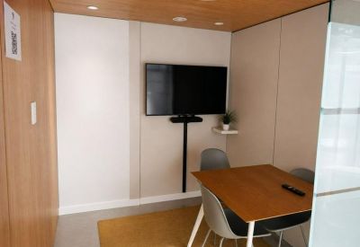 Small private meeting room with a wall-mounted TV and wooden table.
