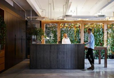 A modern timber-paneled reception desk with lush green vertical gardens in the background.