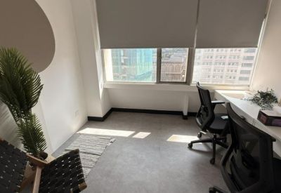 Private office with two desks, potted plant, and large windows with city views.