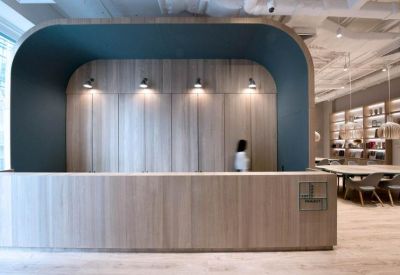 Modern wooden reception desk with a curved teal alcove and warm spotlighting.