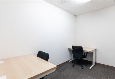 Small private office with two light wood desks and black ergonomic chairs.