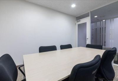 Minimalist meeting room with a light wood table and six black chairs.