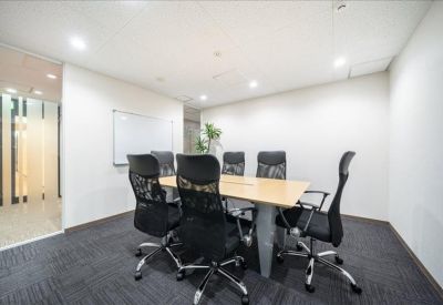 Professional meeting room featuring a wooden table, black ergonomic chairs, and a whiteboard.