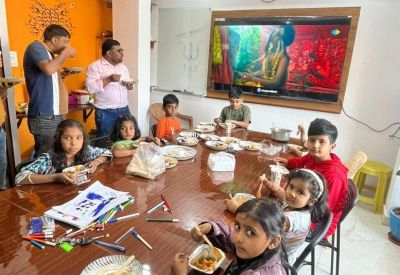 Multi-purpose common room with children at a table and a large screen displaying vibrant media.