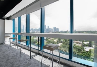 Bright window-side coworking bar with tall stools overlooking the Makati skyline.