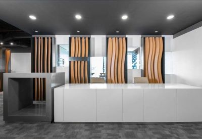 Sleek reception area featuring a long white front desk and decorative wood paneling.