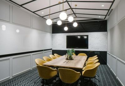 Professional meeting room with a wooden table, mustard yellow chairs, and industrial-style ceiling lighting.
