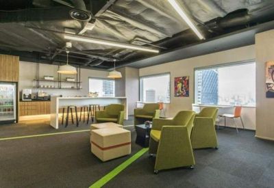 Spacious breakout lounge with green armchairs and a modern pantry bar.
