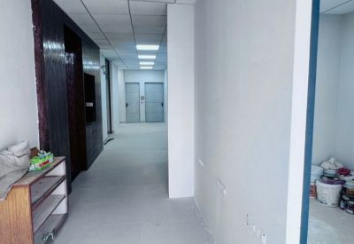 Long white corridor with recessed ceiling lights and doors leading to private office suites.