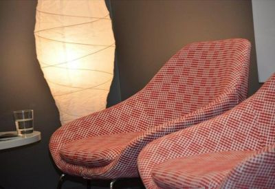 Close-up of pink upholstered armchairs next to a large paper floor lamp.