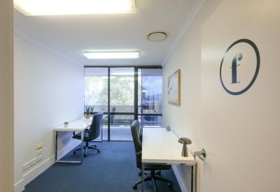 Bright two-person private office suite with white desks and blue carpet.