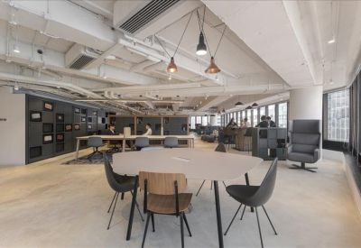 Spacious communal lounge with industrial ceilings, designer pendant lights, and various seating areas.