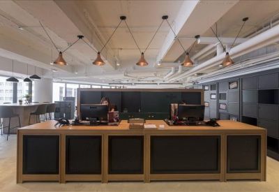 Minimalist reception desk with a light wood finish and multiple monitors.