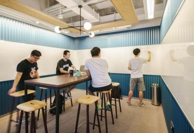 Collaborative room with blue corrugated walls, high tables, and floor-to-ceiling whiteboards.