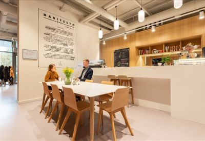 Cafe-style meeting area with a long white table and coffee bar backdrop.