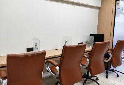 Row of office desks with brown chairs and partitions.