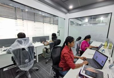 Bright open-plan office with employees working at white desks with laptops.
