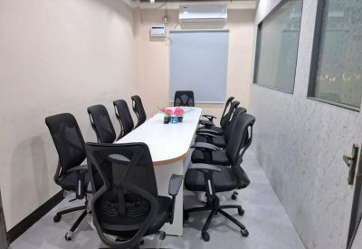 Professional conference room with a long white table and eight black ergonomic chairs.
