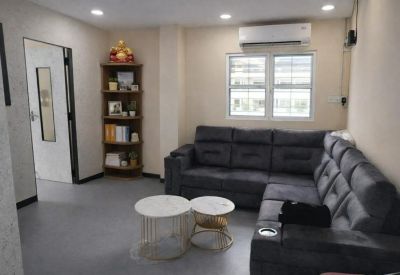Lounge area featuring an L-shaped grey sofa, round nesting coffee tables, and a wooden bookshelf.