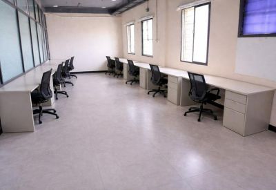 Open-plan workspace with rows of white desks, black mesh chairs, and large windows.