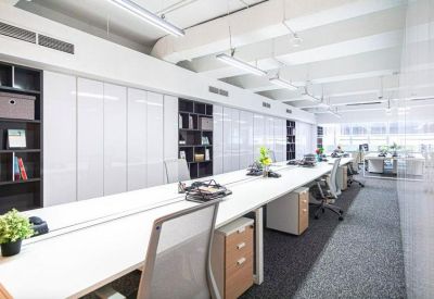Open-plan workspace with long white desks, ergonomic chairs, and integrated storage units.
