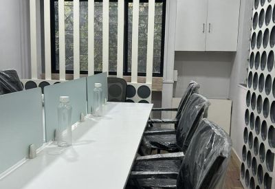 Modern open-plan office at Yash Coronet featuring white desks with glass dividers and ergonomic chairs.