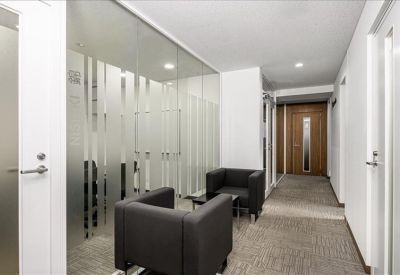 Modern hallway with glass partitions and a small seating area with armchairs.