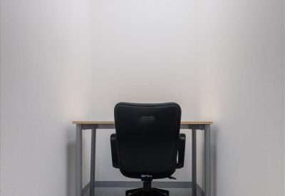 Private windowless workstation booth with a grey carpet and a black ergonomic chair.