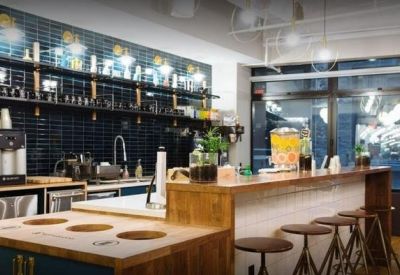 Modern office pantry and kitchen area with blue tiled backsplash and bar seating.