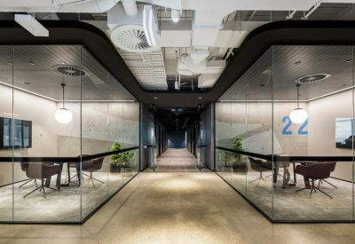 Symmetrical view of two glass-walled meeting rooms flanking a central corridor with exposed ceilings.