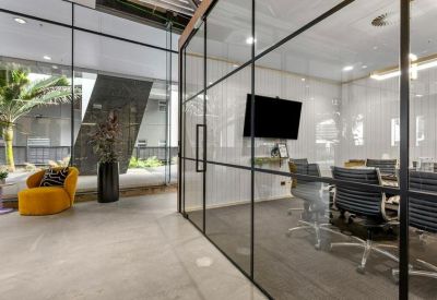 Glass-walled meeting room with a wall-mounted TV screen and conference table.