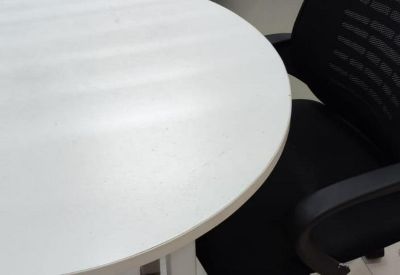 Four-person collaborative workstation unit with white surfaces and black chairs.
