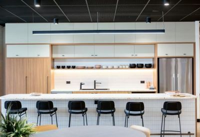 Modern communal kitchen area with a large marble island bench and sleek black stools.