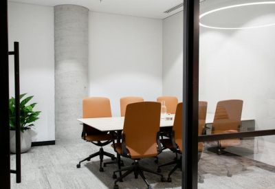 Professional meeting room with tan leather chairs and a circular overhead light fixture.