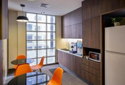 Communal kitchen area with dining tables and bright orange chairs.