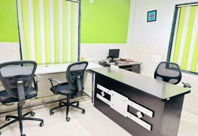 Office workspace featuring a large black desk and ergonomic mesh chairs against a vibrant green wall.