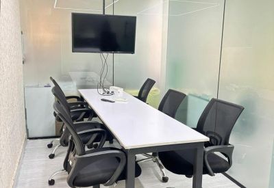 Professional meeting room with a white conference table, black mesh chairs, and frosted glass walls.