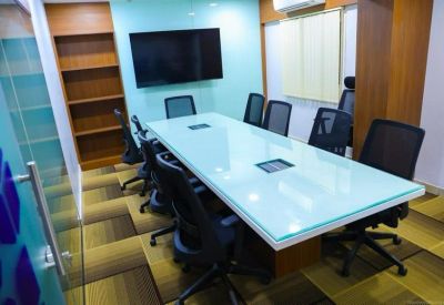 Professional meeting room featuring a large glass table and wall-mounted screen.