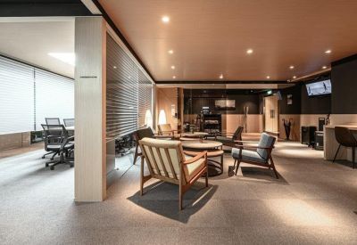 Spacious communal lounge with mid-century modern armchairs and warm overhead lighting.