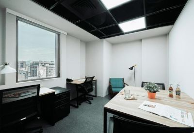 Modern private office with two desks, a meeting table, and city views through a large window.