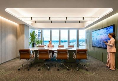 Professional boardroom with a long white table, leather chairs, and a large presentation screen.
