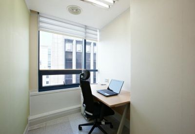 Small private office with a single desk, laptop, and city view.