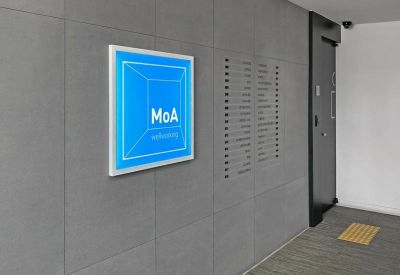 Concrete-textured wall featuring a blue MoA sign and a directory of building tenants.