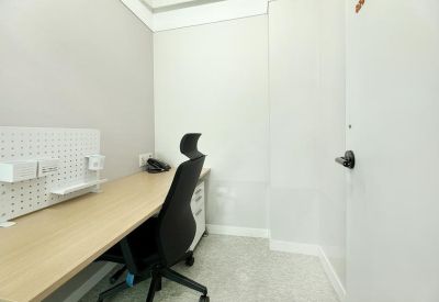 Private office suite with a wooden desk, black ergonomic chair, and pegboard organizer.