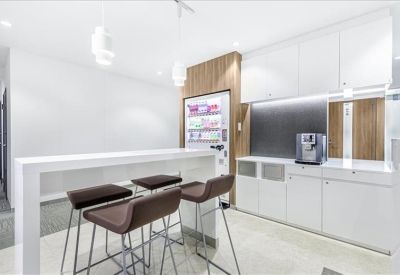 Modern communal kitchen area with a white breakfast bar and coffee machine.
