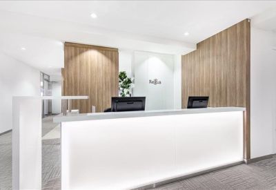 Bright white reception desk with glowing base and wood panel accent walls.